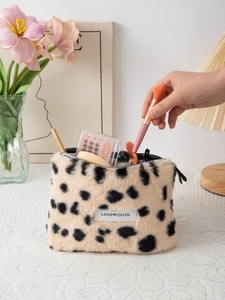 Cosmetic bag detail showing faux fur texture with brushes and lashes on a white desk