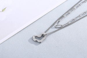 Macro shot of silver-colored layered metal chains with textured heart pendant detail