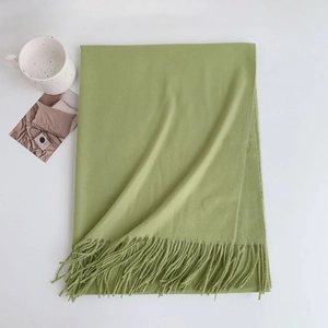 Close-up of soft green faux cashmere scarf featuring decorative fringe tassels on white background