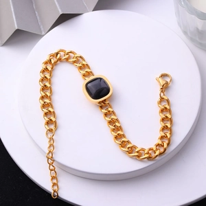 Vue détaillée d'un bracelet gourmette doré orné d'une pierre précieuse noire carrée