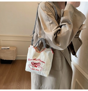 Detail of white nylon crossbody bag with cherry embroidery and checkered shoulder strap