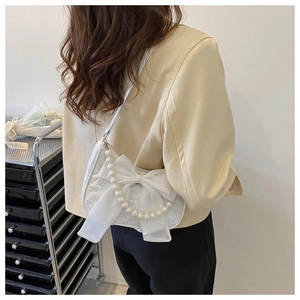 Detailed back view of a white bow shoulder bag with pearl chain shown on a model