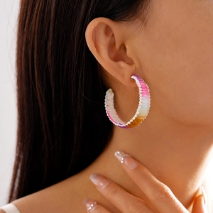 Macro detail of vibrant gradient woven rope C-shape hoop earrings on a model