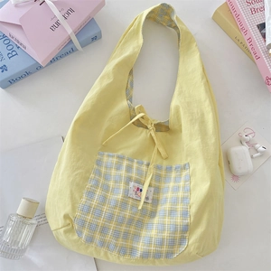 Close-up of yellow summer hobo bag with blue checkered pocket and bow tie detail