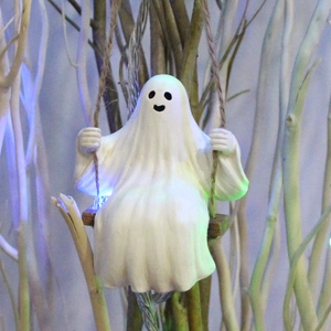 Ghost on wooden swing figurine detail with eerie blue and green lighting for Halloween