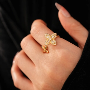 Gros plan d'une bague trèfle dorée avec pierres en zircon brillant sur la main