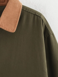Detailed view of army green jacket with a brown corduroy collar and high-quality stitching