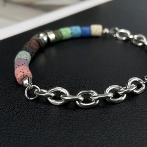 Detailed close-up of volcanic stone beads and silver bamboo chain link bracelet on black leather
