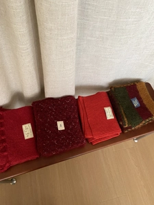 Detalle de bufandas de punto grueso rojas y burdeos dobladas sobre un banco de madera
