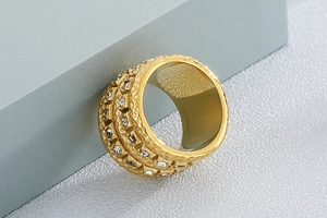 Detail of wide hammered gold ring featuring double rows of inlaid white zircon stones