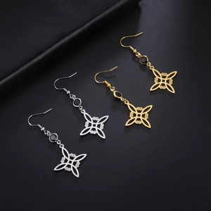 Detail view of symmetrical gold and silver Wicca knot drop earrings on a black leather stand