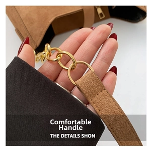 Detail of golden ring chain and fine stitching on brown suede handbag strap