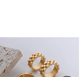 Macro shot of stainless steel rings with geometric grid texture in gold and silver finish