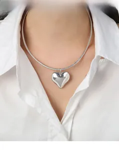 Close-up of minimalist silver heart pendant necklace styled on a white shirt