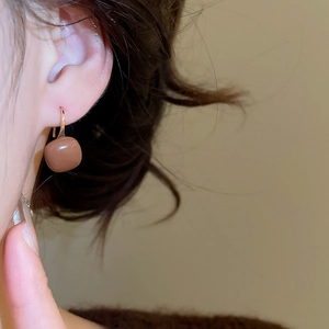 Macro side view of a model wearing brown square resin tiger eye earrings in C-shape
