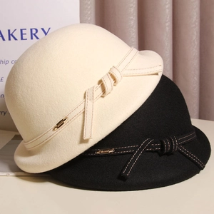 Detail of wool cloche hats with bow decoration and metallic tag in cream and black