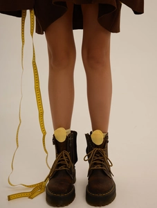 Detail of dark brown leather platform boots with bright yellow laces and chic texture