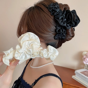 Detail of elegant pleated fabric floral hair claw with a soft silky satin texture finish