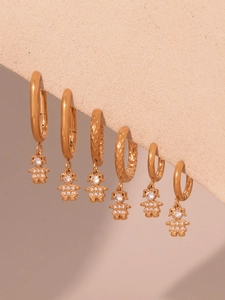 Detailed macro view of three golden mini hoop earrings with zircon girl-shaped pendants