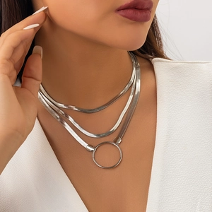 Close-up of triple-layered silver snake chain necklace featuring a polished ring pendant