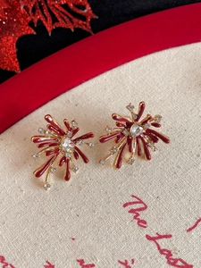 Macro shot of firework-shaped stud earrings with ruby red enamel and sparkling crystals
