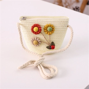 Detailed view of kids' cream straw bag with floral and ladybug accents on white background