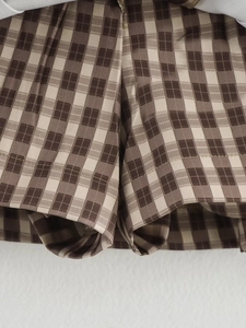 Vista macro dettagliata della trama del tessuto a quadri marroni e dell'orlo della gonna