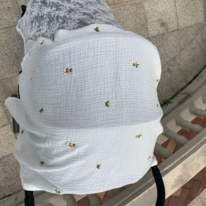 Detail of breathable white stroller sunshade cover with orange fruit embroidery texture