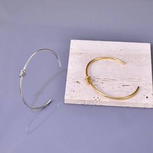 Detail showing knot design on gold and silver polished stainless steel open bracelets