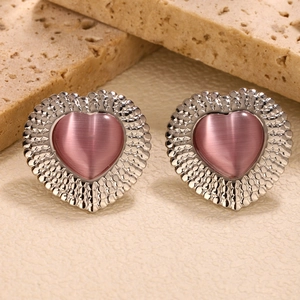 Detailed macro view of heart-shaped pink cat-eye stone earrings in silver metal setting