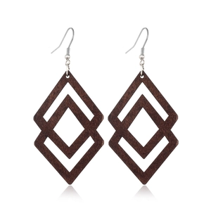 Close-up of interlocking wooden geometric rhombus earrings with metallic hooks on white
