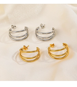 Detail view of gold and silver C-shaped triple hoop earrings on champagne satin