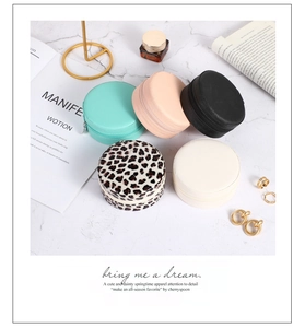 Detailed arrangement of five colorful round portable leather jewelry boxes on marble surface