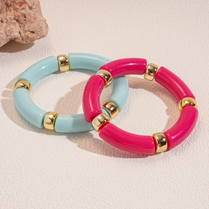 Dettaglio dei bracciali in perline di bambù in acrilico rosa e blu con distanziatori dorati