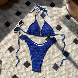 Royal blue smocked bikini set with halter top and high cut bottoms on a textured rug