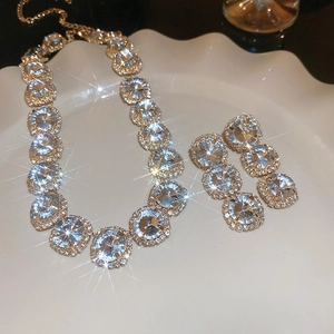 Close-up of gold-plated necklace and earrings set with sparkling round crystals