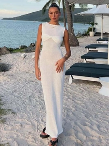 Elegant white sleeveless knit maxi dress with halter neck and beach resort scenery