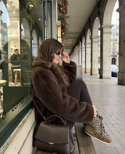 Deep brown faux fur jacket styled with slim pants and boots in an urban street setting