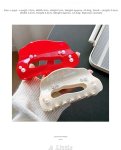 Detail of acetate shark hair clips with faux pearls in red and cream white finishes