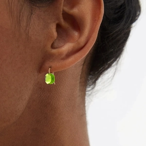 Dettaglio degli eleganti orecchini con gemma verde a cuscino e ganci dorati