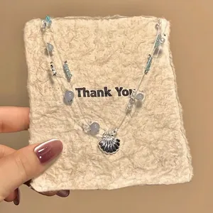 Elegant seashell pendant necklace with blue beads and pearls on a gift card display