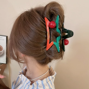 Détail de la pince à cheveux en acrylique bicolore vert et orange avec perles rouges