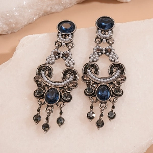 Vintage oval earrings with blue gemstone, pearls, and tassels on a natural stone base