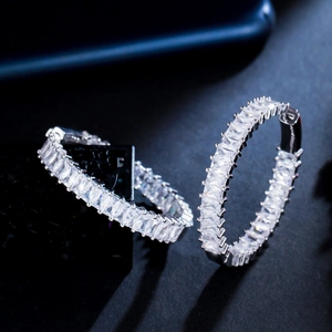Macro view of C-shaped silver earrings with brilliant channel-set zircon stones