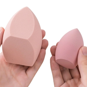 Set of two soft makeup sponges in light and deep pink shown in hand for size contrast