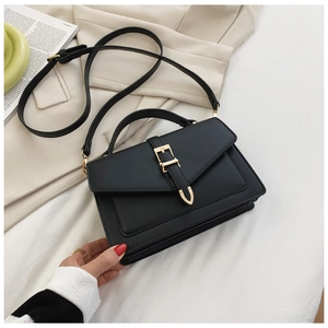 Detail of black faux leather crossbody bag with gold hardware and adjustable shoulder strap
