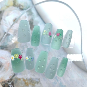 Detailansicht matter grüner Kunstnägel mit 3D-Wassertropfen und Blumenmustern
