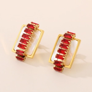 Detailed macro view of gold-plated rectangular earrings with red zircon and mother of pearl