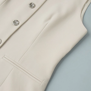 Detail of cream suit vest featuring embossed silver buttons and fine textured fabric