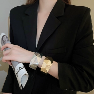Detail der gebürsteten Metalltextur und des geometrischen Designs des offenen Manschettenarmbands